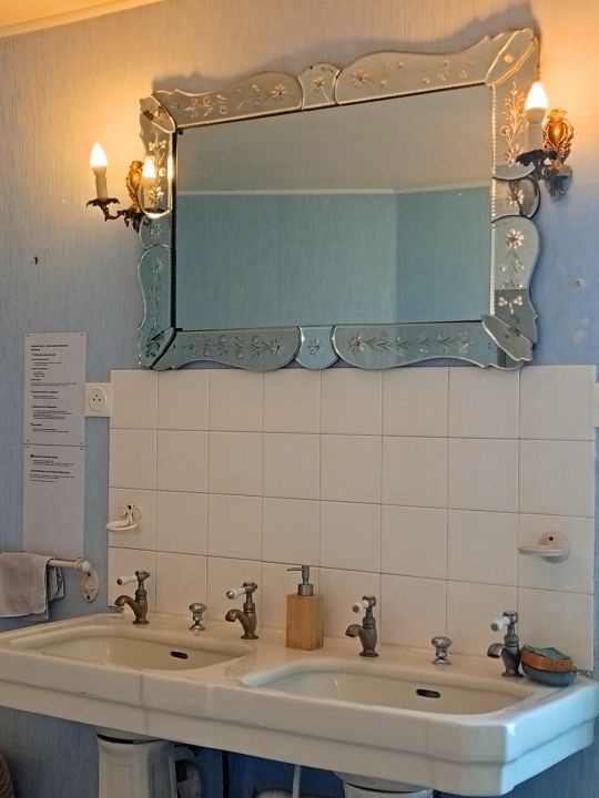 La Salle de Bain Belle Époque — 13 m² avec douche, baignoire, double vasque et de beaux éléments rétro : lavabos sur colonnes, miroir ancien biseauté et détails qui évoquent les salles de bain d'une autre époque.<br /> La Salle de Bain Belle Époque — 13 m² avec douche, baignoire, double vasque et de beaux éléments rétro : lavabos sur colonnes, miroir ancien biseauté et détails qui évoquent les salles de bain d'une autre époque.<br />